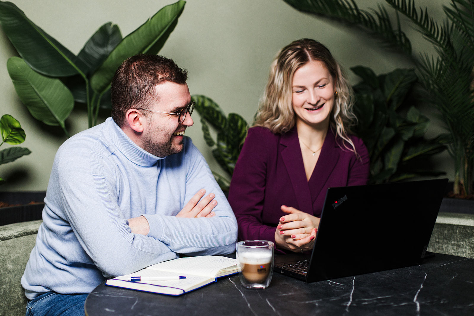 een vrouw en een man zijn als collega's aan het overlegggen terwijl ze op een laptop kijken